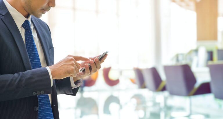Businessman using mobile phone with blur bank office background with bokeh light